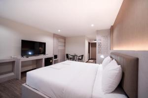 a bedroom with a white bed and a television at The Y House in Chiang Mai