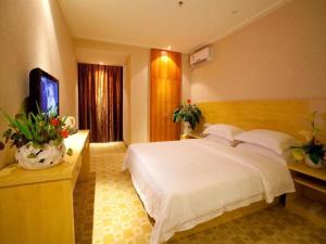 a bedroom with a large white bed and a television at Nanning Hawks Holiday Hotel in Nanning