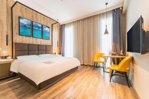 a hotel room with a bed and a desk and a table at Qingdao Elegance Hotel in Qingdao