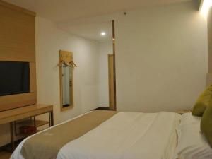 a bedroom with a bed and a flat screen tv at GreenTree Inn Heze Changcheng Road Tianhua E-commerce Logistics Park Express Hotel in Heze +56 photos
