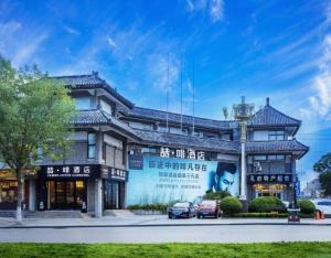 a building with cars parked in front of it at James Joyce Coffetel Qufu Tourist Center Gulou Street Sankong Scenic Spot in Jining