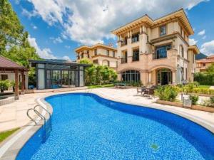a mansion with a swimming pool in front of a house at Guangzhou Xiangjiang Health Valley in Huangpu