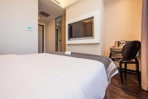 ein Hotelzimmer mit einem weißen Bett und einem Stuhl in der Unterkunft Xana Lite Hotel Tianjin National Exhibition Center Jinnan University Town in Tianjin + 60 Fotos