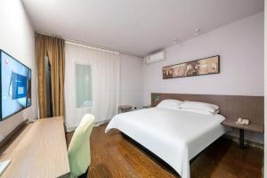 une chambre avec un grand lit blanc et une télévision dans l'établissement Magnotel Hotel Shanghai Railway Station Magnolia Plaza, à Shanghai
