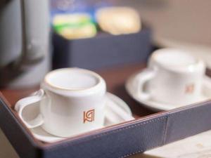 zwei weiße Tassen und Untertassen auf einem Tisch in der Unterkunft Borrman Hotel Zhanjiang Xuwen Port Terminal in Xuwen