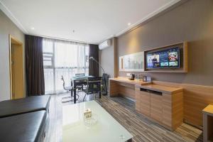 a living room with a tv on the wall and a table at City Comfort Inn Lichuan Railway Station Tenglong Cave in Datang