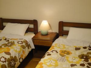 1 dormitorio con 2 camas y mesita de noche con lámpara en Farm Inn Anima no Sato, en Abashiri