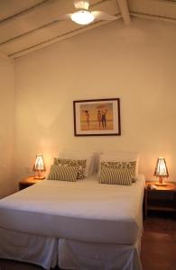 a bedroom with a large white bed with two lamps at Jardim de Trancoso Pousada in Trancoso