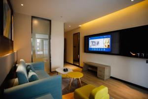 een woonkamer met een blauwe bank en een tv bij IU Hotels· Xincheng Haibing University Store in T'ao-hua Tao