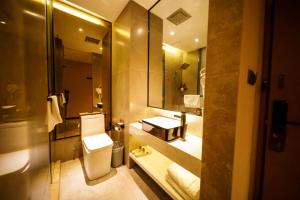 een badkamer met een toilet en een grote spiegel bij IU Hotels· Xincheng Haibing University Store in T'ao-hua Tao
