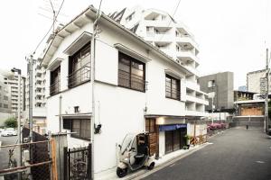 ein weißes Haus mit einem Roller auf einer Straße geparkt in der Unterkunft Araiya Tokyo -Private Townhouse- in Tokio