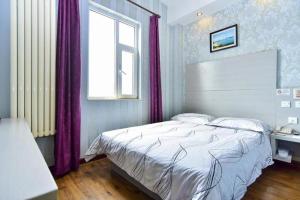 ein Schlafzimmer mit einem Bett mit lila Vorhängen und einem Fenster in der Unterkunft City 118 Hotel Qingdao Licang Pedestrian Street in Laoshan + 199 Fotos