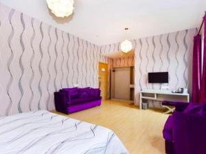 ein Schlafzimmer mit einem Bett, einer Couch und einem Fernseher in der Unterkunft City 118 Hotel Qingdao Licang Pedestrian Street in Laoshan