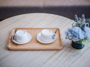 a tray with two coffee cups and a vase of flowers at Echarm Hotel Nanning Dongge Macun Metro Station in Nanning