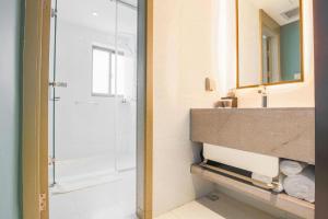 ein Badezimmer mit Dusche, Waschbecken und Spiegel in der Unterkunft Magnotel Hotel Huangshan Scenic Area Transfer Center in Huangshan Scenic Area + 106 Fotos