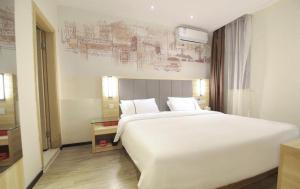 a bedroom with a large white bed and a drawing on the wall at City Comfort Inn Changsha Window of the World Zhongmao City in Changsha