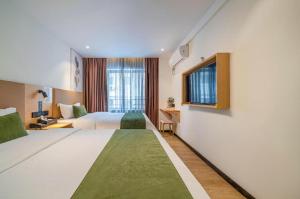 une chambre d'hôtel avec deux lits et une fenêtre dans l'établissement Green Tree Inn Guangxi Wuzhou 2nd Xinxing Road Liangguang Market, à Wuzhou