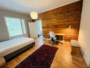 a bedroom with a wooden accent wall and a bed and a desk at Villa Kuninkaankivi in Kalajoki