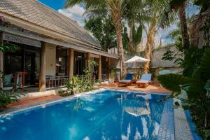 a swimming pool in front of a house with palm trees at My Dream Boutique Resort in Luang Prabang