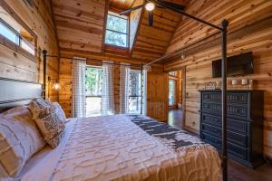 une chambre avec un lit dans une cabane en rondins dans l'établissement Pine and Pickle - Cozy Cabin, Sleeps 10, Loft, Hot Tub, Firepit, à Stephens Gap