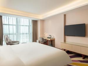 a hotel room with a bed and a flat screen tv at Lavande Hotel Zhongshan Xiaolan Taifeng in Jilong