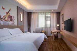 a hotel room with a white bed and a television at Vienna Hotel Yunnan Dali Ancient City Scenic Spot in Dali Ancient Town