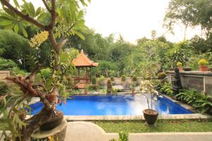 a swimming pool in a garden with a gazebo at KT. Kuaya Home Stay in Ubud