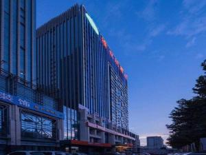 un grand bâtiment avec une enseigne sur le côté dans l'établissement Vienna Hotel Henan Luoyang Jiudu Road Wanda, à Luoyang