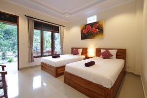 um quarto com duas camas e um quadro na parede em KT. Kuaya Home Stay em Ubud