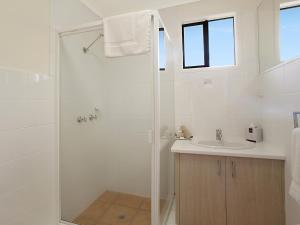 a white bathroom with a shower and a sink at Cayman Quays in Noosaville