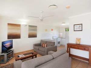 a living room with a couch and a tv at Cayman Quays in Noosaville