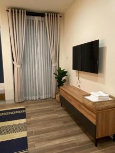Una sala de estar con un televisor de pantalla plana en la pared. en Eat Sleep Chann, en Chanthaburi