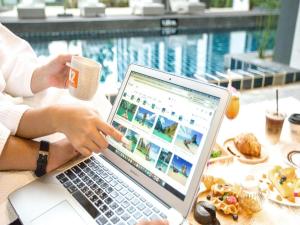 Una mujer sentada en una mesa con una computadora portátil en B2 Krabi Ao Nang Premier Resort, en Ao Nang 