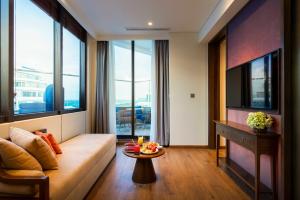 a living room with a couch and a tv at Apec Nirvana Peace Mui Ne in Mui Ne