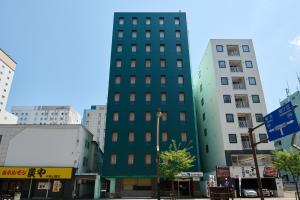 a tall green building in the middle of buildings at Hotel Sho Sapporo - Vacation STAY 55602v in Sapporo