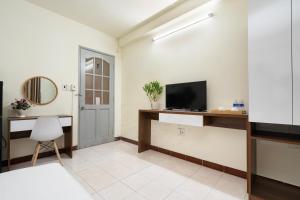 uma sala de estar com uma televisão e uma secretária com uma cadeira em Phan Hotel em Cidade de Ho Chi Minh