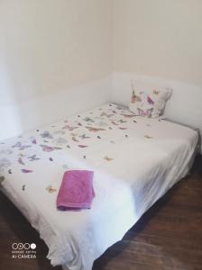 un letto bianco con un asciugamano viola di Chambre à petit budget pour personne simple a Saint-Laurent-de-Neste