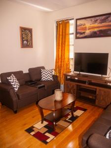 a living room with a couch and a flat screen tv at Immaculate furnished 1-Bedroom Apartment in Sunnyside