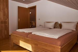 1 dormitorio con cama de madera con sábanas blancas en Ferienwohnung Achhammer, en Riedenburg