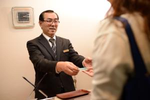 un hombre con traje y corbata sosteniendo un celular en Hotel Park Sendai 2, en Sendai