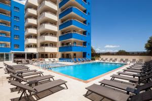 una piscina con tumbonas frente a un edificio en Ibiza Heaven Apartments, en Playa d'en Bossa