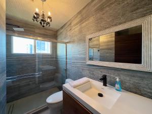 a bathroom with a sink and a toilet and a mirror at Aqua Tower 3BR-3BA Beachfront Condo in Playas de Tijuana in Tijuana