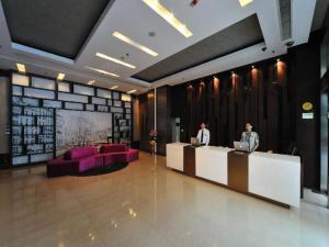 two people standing at a desk in a lobby at Kingtown Hotel Hongqiao Shanghai in Shanghai