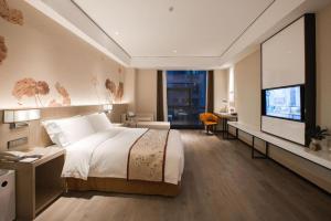 a hotel room with a bed and a flat screen tv at GRACE Select Hotel (Kunshan Huaqiao International Convention Center) in Suzhou