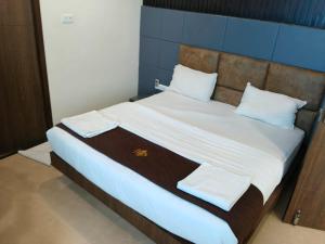 a bed with white sheets and towels on it at Senthur Inn By K Hotels in Vellore