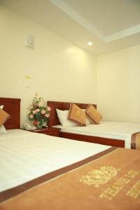 a room with two beds and a vase with flowers at Hotel Thanh loi in Mỹ Ðuc