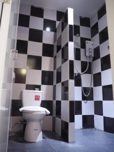 a bathroom with a toilet and a black and white checkered wall at At night Airport Resort in Patong Beach +139 photos