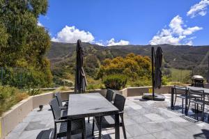 a table and chairs on a patio with mountains in the background at Lantern 13 - Deluxe Terrace in Thredbo +6 photos