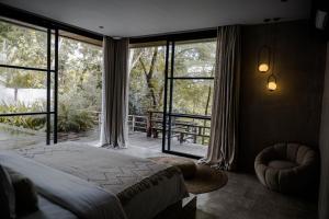 a bedroom with a bed and large glass windows at Aranya Bali in Tumbak Bayuh