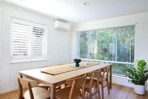a dining room with a table and chairs and windows at Casa Katharina – Your Coastal Escape on Noosa Hill in Noosa Heads